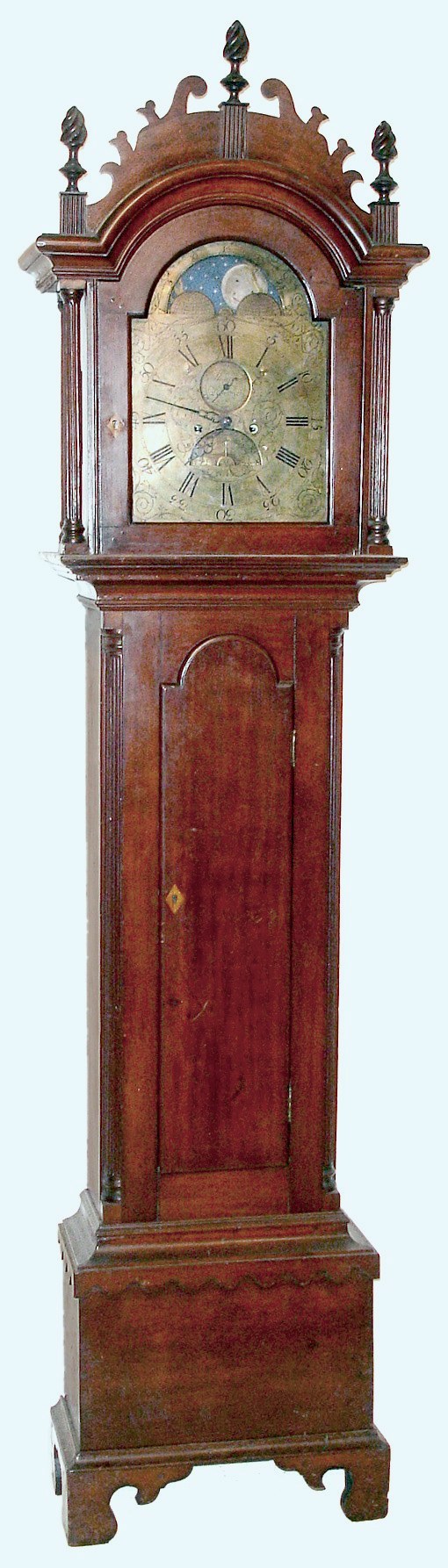 Nathaniel Shipman, Norwich, Conn., tall case clock 8 day time and strike brass movement in cherry case with bracket base, quarter reeded columns, wooden capitals, whale's tail frets, flame finials, tombstone door and scalloped skirt. The brass dial is signed "Shipman Norwich" with moon phases, second hand, and calendar above 6, c1790 — Antique Clocks Price Guide