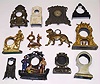 Twelve cast-metal clock cases. Includes multi-color pirates, standing dog, seated woman, standing soldiers, MOP iron-front, cuckoos, woman harpist novelty, etc.