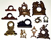Eleven small clock cases. Includes two wood tambours, one mini China, and cast-metal cases of crouching lion, sailing ship, anchor, standing nymph, Native Americans, etc.