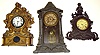 Three large 8-day cast metal mantel clocks. Detailed elaborate castings. Two column has 3 barrel pendulum. Smallest has cute begging hare. Largest is 22" high.