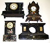 Four decorated black clock cases. 3 with dials. 2 iron fronts with lavish MOP inlay. 1 iron with cast feet and lion head handles. 1 French marble. Tallest is 16" high.