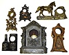 Six cast-metal clock cases. Includes great novelty case with standing figures and dolphin, a 1492 Columbus, an advertising for Kentucky whiskey and an oversize case with two standing female figurals.