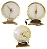 Three Jefferson Golden Hour electric mystery clocks. Intact cases and glasses, one missing its red base cover.