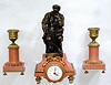 French, miniature 3-piece garniture desk set, salmon colored marble and bronze figure with ormolu trim, and with a tiny round French movement and fancy porcelain dial, and tiny pierced and chased gilt hands. Note seated warrior in tunic is well detailed and he wears a helmet of tooled leather over the top of a bear's head, c1880