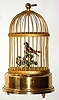 Swiss, Reuge, singing bird in cage, a red-breasted robin with blue cheek feathers setting on a perch in a gold toned brass cage, c1930