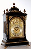 English, triple fusee, quarter chiming bracket clock, in a classic Georgian style large ebonized case with brass caryatids, side frets and pineapple finials, the whole resting on cast "toed" feet, chiming your choice of Whittington on 8 bells or Westminster on 4 large flat wire gongs, and then sounding the hours on a still larger steel flat wire gong, the clock retailed by O. A. Strapp, Cambridge, and with an engraved cartouche below 12 bearing that information, and the arched dial with small subsidiary dials labeled Chime /Silent, F/S, and Chime on 8 Bells or Westminster, C.1875