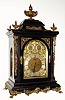German {in the English style} large fusee bracket clock, retailed at 29 Church St, Liverpool by Frisch Schierwater and Co (on dial), an ebonized case with cast brass "jester" caryatids to the corners, fancy cast brass side frets, all surmounted by a giant urn and flame finial, with smaller finials to the corners, the whole resting on "toed" feet. Note this clock chimes Westminster quarters on 4 tuned flat wire gongs and strikes the hours on a much larger 5th deep toned gong. Subsidiary dials on the arched dial are for Fast / Slow and Chime / Silent. The dial with cast spandrels of winged cherubs on both the dial corners and at the apex of the arch, and gilt foliate castings filling in other areas. Note this is a two [2] fusee clock, with reliable quarter chime and strike system designed by Winterhalder and Hofmeier....see horizontal pins on rear of tune drum to perform strike. C.1890
