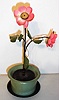 Desk clock German two rose plant with fabric petals and leaves in painted cast metal pot with Arabic numeral dial inset into center of upper rose, stem wind and stem set movement concealed in pot, c1930
