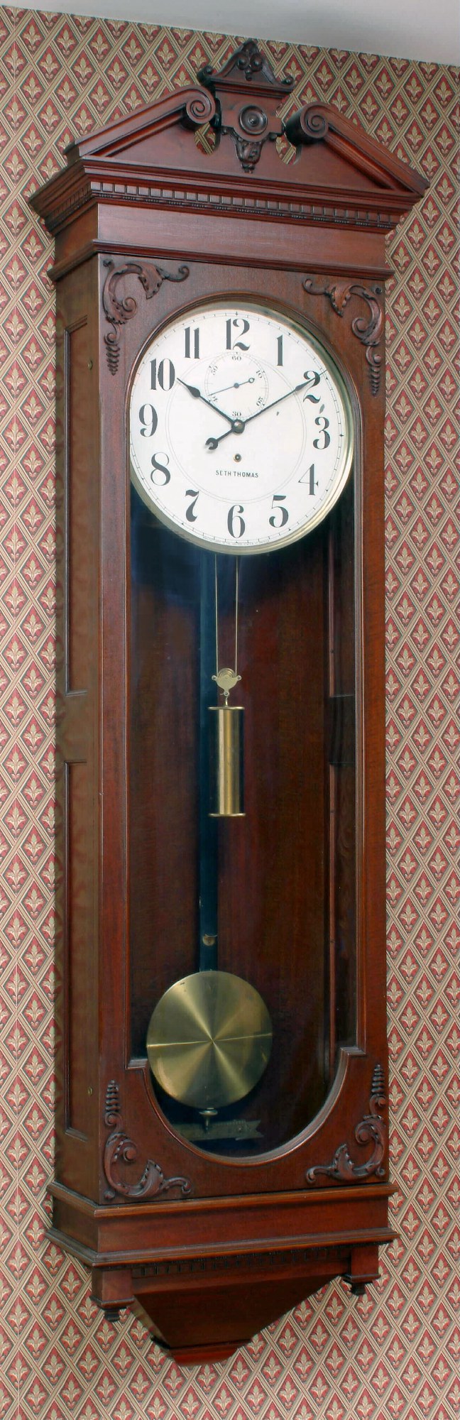 Seth Thomas Clock Co., Thomaston, Conn., "REGULATOR No. 63", large walnut hanging wall clock, weight driven, 8 day in an attractive case with dentil molding along cornice and a pediment top with finely carved trim. From the Bob Wasserman collection, c1887. — Antique Clocks Price Guide