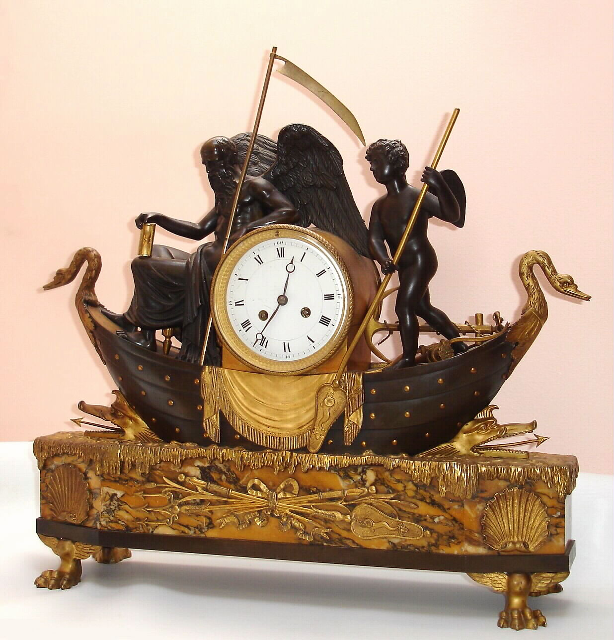 French, Love and Time, Bronze and Marble mantle clock, depicting Father time or Chronos with his scythe, sitting in a boat, steered by the cherubic Amor, and with a quality movement by Vincenti (1855 award medallion), the bronze boat and "water" mounted to a well figured piece of yellow / black striped marble, the whole supported on 4 large paw feet, c1875. — Antique Clocks Price Guide