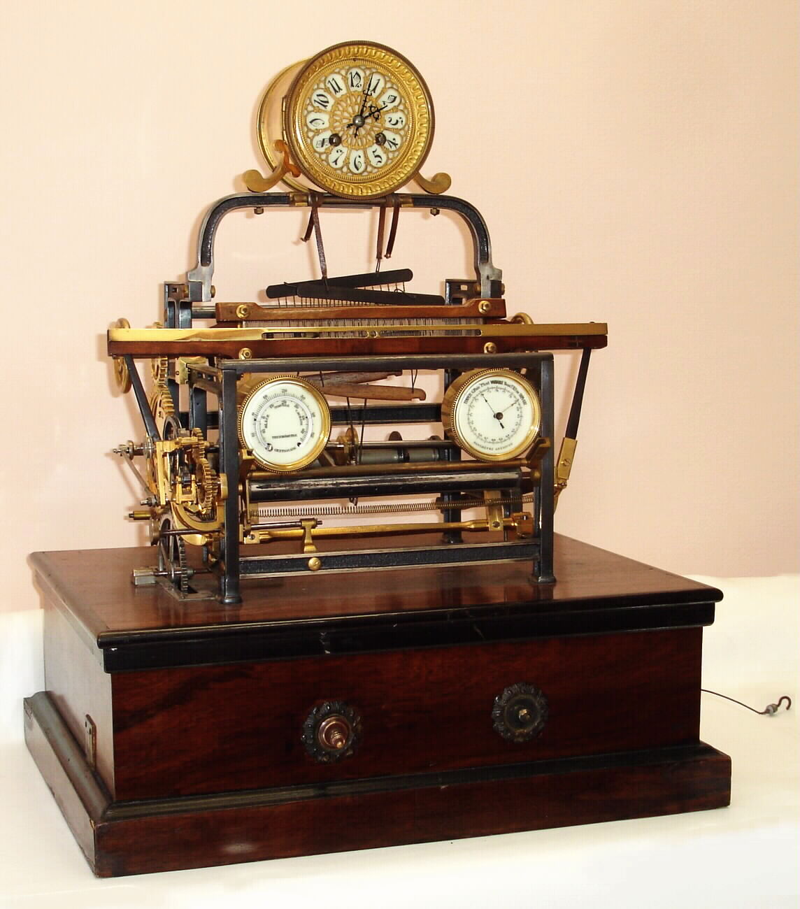 French, Guilmet, rare automaton "LOOM" from the industrial series, a conventional time and bell strike movement, with the exposed gears and loom driven by a weight falling down the right side of the base, the "motor" for the loom, a large heavily made clockwork movement with dual vane fan governor. Typical of Guilmet's designs, the loom includes a thermometer to the left and an aneroid barometer to the right , c1880 — Antique Clocks Price Guide