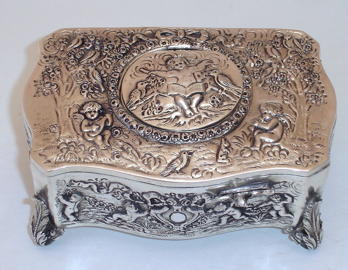 German, Singing Bird in a .925 Silver box, embossed with images of children playing the flute and lute, also conducting. This is not an old box, probably, c1995 — Antique Clocks Price Guide