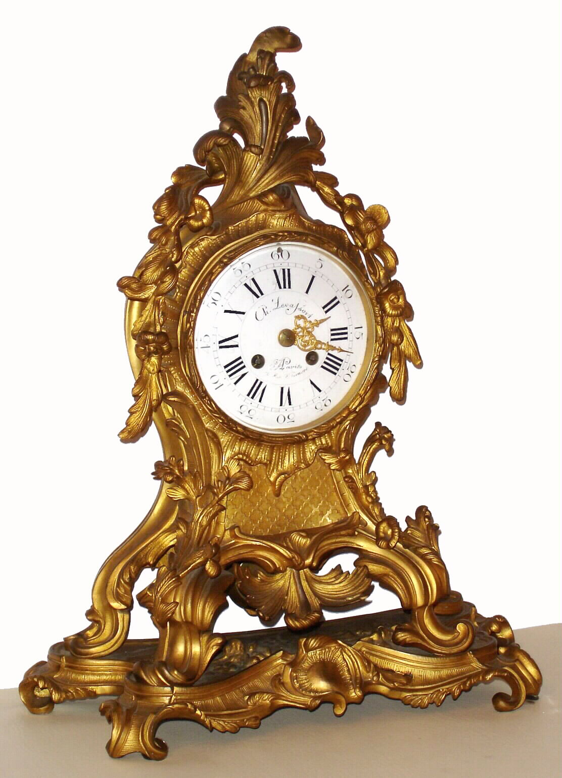 French mantel clock for Ch. Levassort, in the Louis XV style, 8 day, time and strike, spring driven movement in an ornate ormolu case with floral decor and white enamel dial, the main case with an integral base, c1880 — Antique Clocks Price Guide