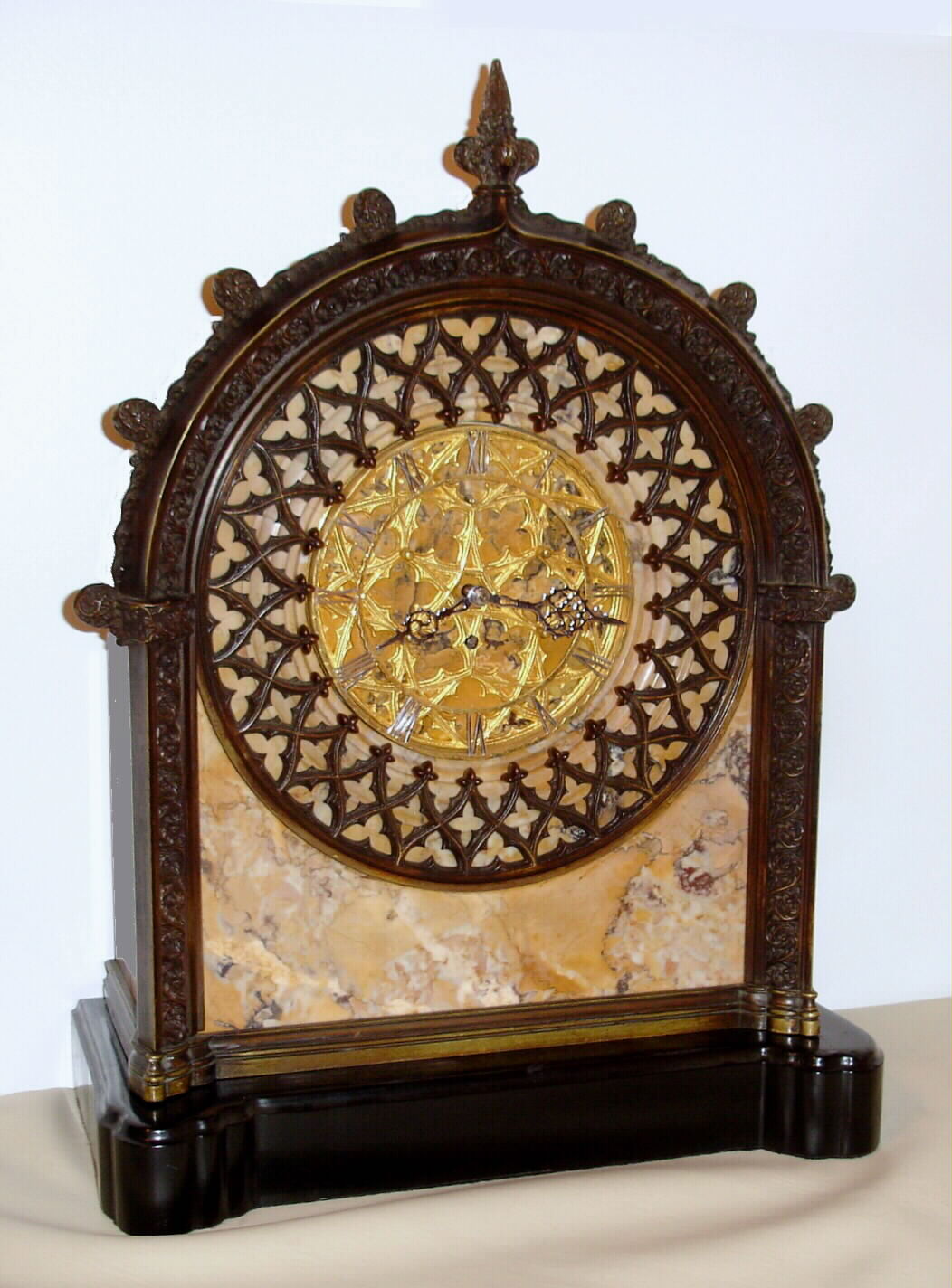 E.F. Caldwell, New York mantel clock with E. Howard and Co., Boston, 8 day, time only, spring driven, nickel damascene movement with lever escapement and is housed in a very heavy marble case with intricately cast Gothic style bronze case trim resting on conforming ebonized wooden base. The cut brass chapter ring has nickel plated Roman numerals and hands, c1915 — Antique Clocks Price Guide
