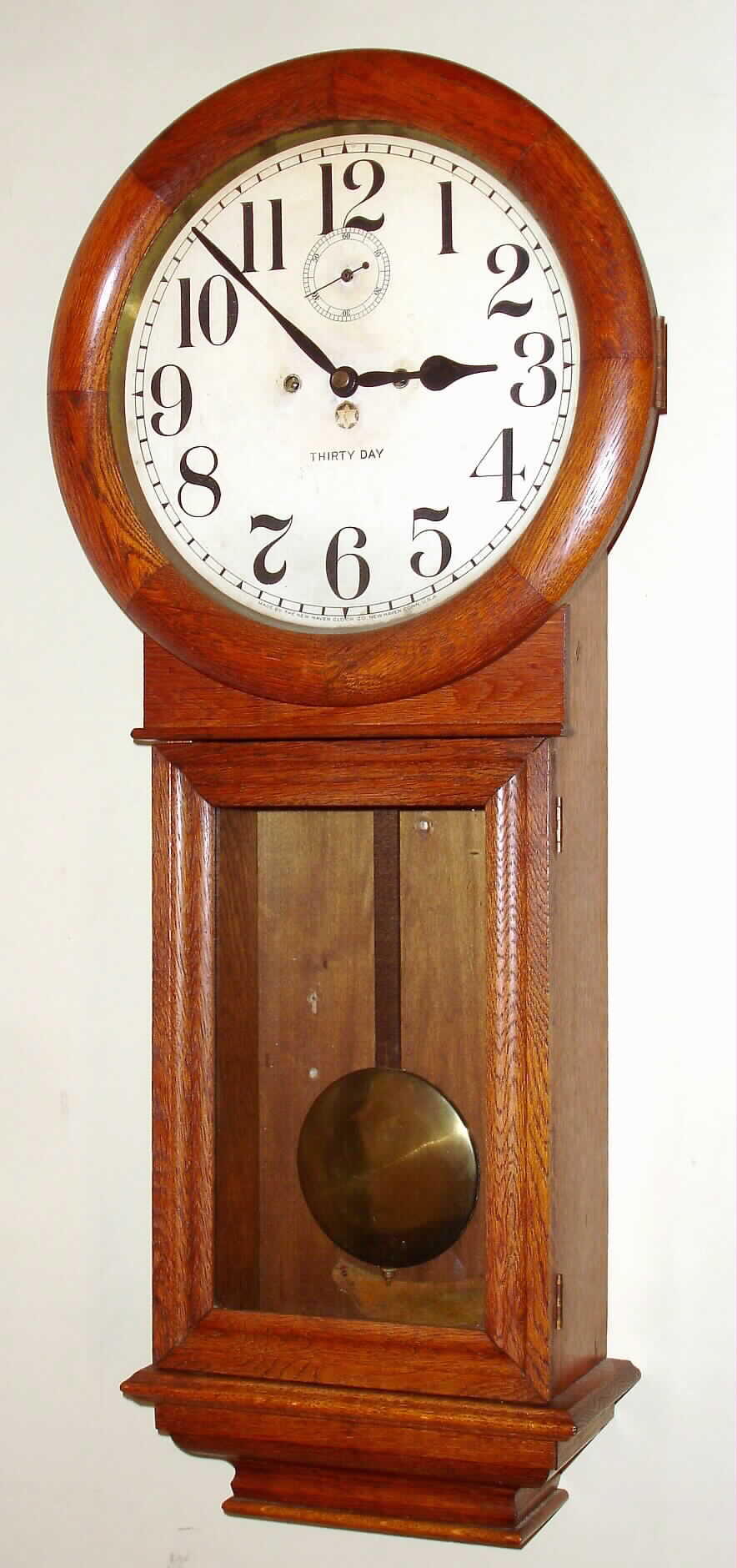 New Haven Clock Co., New Haven, Conn., "Saturn" wall clock, 30 day, time only, double spring driven movement in oak case with painted metal dial, c1911 — Antique Clocks Price Guide