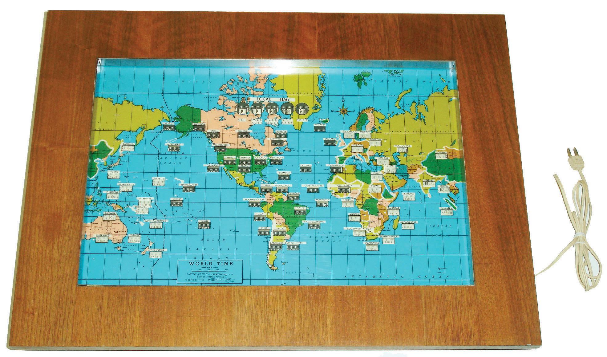 World Time Corp. electric illuminated world map clock, sold by Howard Miller, U.S.A., hardwood veneer over plywood, with glass face, copyright 1959 — Antique Clocks Price Guide