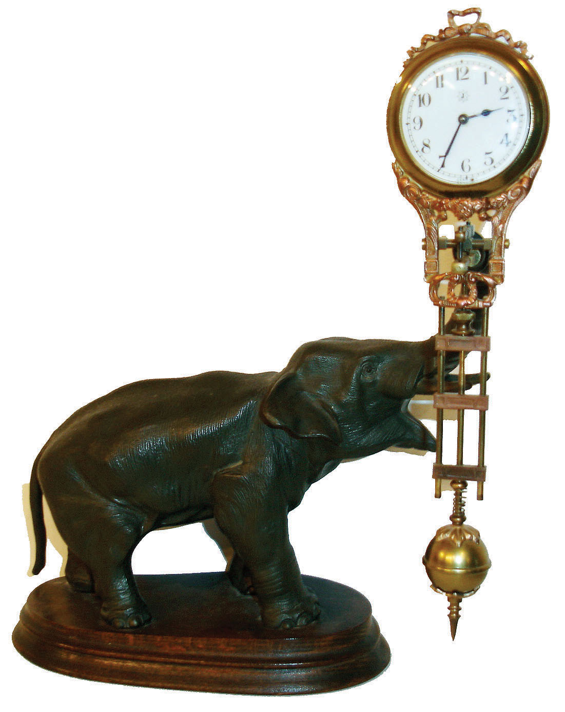 Junghans, Germany,  "Elephant" model swinger, 8 day novelty timepiece, the patinated spelter elephant mounted to a molded beech wood base, his trunk supporting the gilt and patinated clock case/ pendulum, white enamel Arabic numeral dial with junghans logo, blued steel hands, 8 day time only movement, signed "Junghans Germany",ca.1920 — Antique Clocks Price Guide