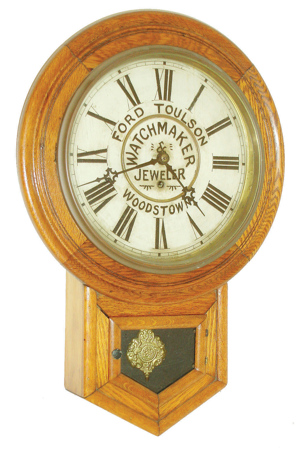 Waterbury Clock Co., Waterbury, Conn., short drop wall clock, 8 days, time only, spring driven movement in an oak case with advertising on painted metal dial "FORD TOULSON WATCHMAKER &amp; JEWELER WOODSTOWN,", c1900 — Antique Clocks Price Guide