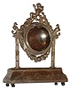 Continental desk or bedside clock case, purpose made to contain the inner case and movement of an earlier pair cased watch, bombe base on ball feet with square columns supporting the round case, with cast floral swag and putti, the top of each column with an inward facing bird, the base and clock case surfaces decorated with repousse ornament in the rococo style, beaded bezel surround, the back with hinged door bearing a silver standard mark, possibly French, right front foot also with a small letter mark, c1850