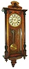 New Haven Clock Co., New Haven, Conn., Vienna regulator style wall clock, walnut case with glazed door and sides, door with turned half columns with ribbed capitals and bases, applied composition ornament, case top piece with applied carving, the base with walnut veneered, deeply molded ogee bracket with central drop, Roman numeral white painted metal dial fixed to a walnut veneered frame with fretwork lower edge, and with fabric backed cutouts below 5:00 and 7:00, blued steel hands, 8 day time and strike movement, c1880