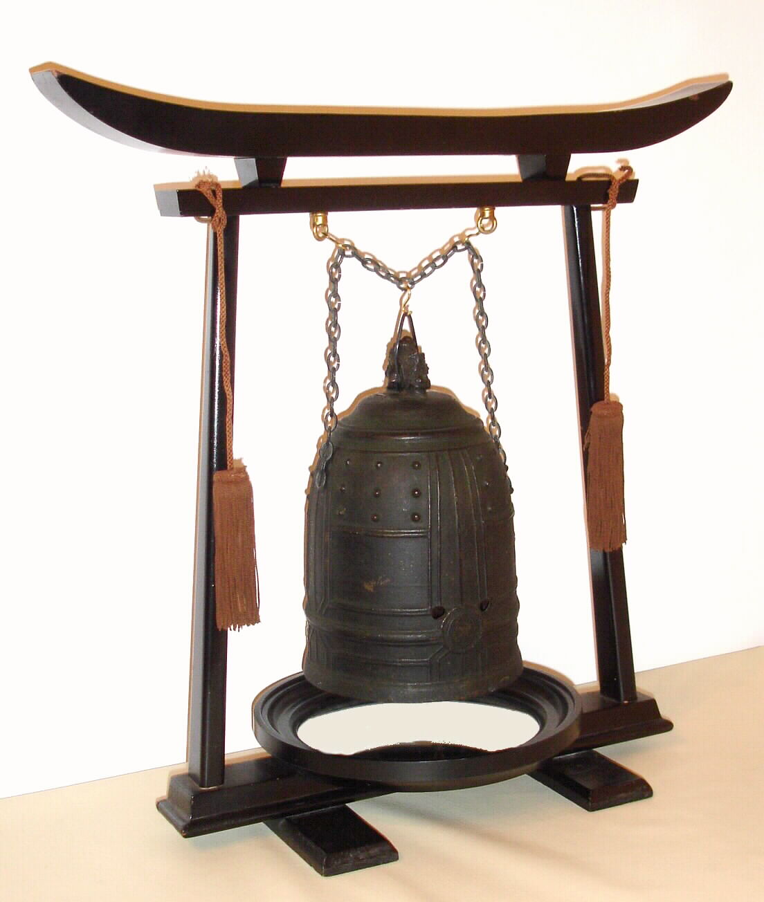 A rare and early Japanese bell clock (Tsurigane Dokei) within a finely cast bronze bell with Japanese characters and double headed dragon form handle; having a posted, iron, double spring driven, striking movement with crown wheel escapement and time regulated by a large circular balance with moveable double weights, originally for adjusting the temporal hours every day before each sunrise and sunset with the change of each Japanese season. The brass dial with single, fixed hand has traditional Japanese numerals 9 through 4 with applied silvered butterflies to the original surrounding dial plate. The rotating dial with adjustable "hour" and "half hour" markers is a common 19th Century upgrade to many very early Japanese clocks that have a single foliot or balance, since changing the weights and hence the rate before sunrise and sunset each day was extremely unhandy. This is verified by J. Drummond Robertson in The Evolution of Clockwork , page 226 saying "we find some of the old clocks "converted" to the new style of motion work. The old fixed hour circle with its revolving centre was removed and the new revolving circle and its fixed hand with adjustable "hour" plates was substituted." This is the case in each of the only other examples of Japanese Bell Clocks of which we are aware: see Japanese Clocks by N.H.N. Mody, plate 113, fig.1 for an almost identical example to the clock being offered. This dial conversion is also apparent in the Bronze Bell Clock sold at Sotheby's Masterpieces From the Time Museum Sale, Part Two, 19 June 2002, lot 126. An inscription on the bell reads Fukushima ya Katsutaro 1689, who may be the maker of either the clock or the bell. Most Japanese spring driven clocks have a fusee to the time train and a going barrel to the strike train. This movement is anomalous, in that is has two going barrels. It may be that the Japanese had not developed a method of turning a fusee at this early date, c1690 — Antique Clocks Price Guide