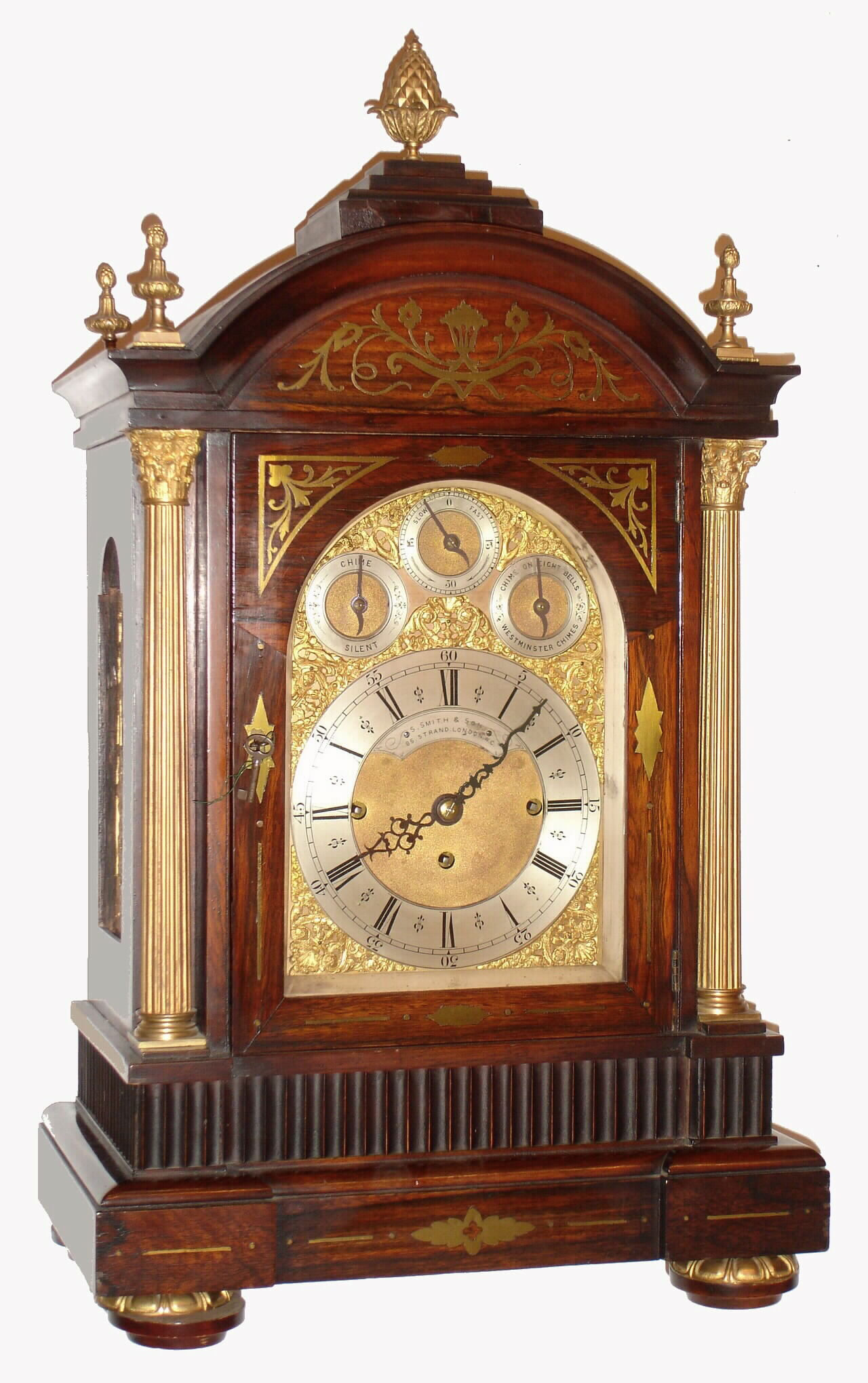 English, John Smith and Son, 85 Strand, London, large 3-fusee, 8-bell, 2-tune, quarter chiming bracket clock, the rosewood veneer case with brass inlay, the door flanked by gilt and reeded brass columns, the side frets of cast brass in the Georgian style, and the arched dial with applied brass spandrels and with 3 subsidiary dials for F/S, Chime/Silent, and 8-bell or Westminster tune. Overall very good original condition, c1890 — Antique Clocks Price Guide