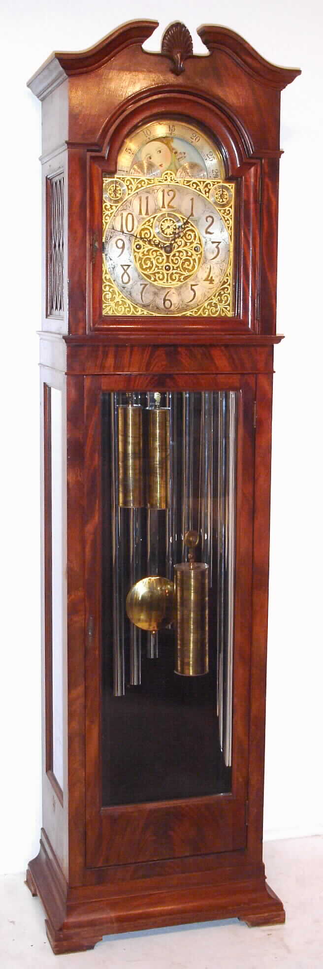 Grand Rapids Clock and Mantel Co., Grand Rapids, Michigan, 9 tube hall clock, 8 day, time, strike and chime, weight driven European movement playing Whittington or Westminster tune in mahogany case with crotch mahogany veneer front and sides and beveled glasses. The brass arched dial has a silvered chapter ring with applied brass numerals, cast spandrels and dial center, moon phase, selection for tunes or silent, and second's bit, c1910 — Antique Clocks Price Guide