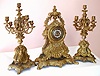 French, large cast brass three piece garniture set with matching candelabras. The cast dial has 12 individual cartouche numerals, and pierced steel hands, now white. Case bears garlands and shell motif and large lions heads flank the clock and smaller lions heads flank the candle stands, c1890