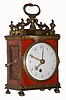Swiss travelling alarm clock, similar to the Pendule d'Officer style, round spring driven movement of two or three day duration with time, grand sonnerie strike on demand and alarm functions, and Sully variant two plane escapement with balance and spring under bridge fixed to the back plate, the pointed escape wheel teeth alternately engaging disc shaped pallets affixed to the balance staff, the time train wound through the dial, the strike and alarm functions wound by cords, gilt brass bezel with beveled convex glass, Arabic numeral white enamel dial, pierced and engraved gilt brass hands, blued steel alarm hand, contained in a dovetailed wooden case covered with tortoise shell, and mounted with gilt brass ornament, the gilt brass gallery with turned finials, cyma curved arms supporting a molded tassel below handle in the form of a snake eating its tail, gilt waterleaf cornice, gilt beaded and molded base on turned feet, brass corners, and gilt rope molding framing lattice panels on sides and back, c1790