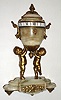 Tiffany and Co., New York, French miniature urn form desk clock with annular dial, time only, spring driven eight day movement with lever platform escapement, the annular dial with Roman numeral white enamel plaques set in a gilt brass ring, signed Tiffany and Co., New York at 12:00, fleur de lis form indicator for time, the polished agate urn with gilt handles, supported by two wingless cherubs, polished agate base decorated with gilt brass laurel appliques on gilt toupie feet, c1890