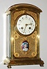French crystal regulator in fancy polished brass case, spring powered time and strike movement, heavy beveled glasses on sides, back and top, the front with latticework panels backed with brass, decorated in a moire pattern, with an enamel portrait of a lady in formal attire below dial, on a transparent violet enamel background, showing a moire patterned ground beneath, molded bezel with beveled convex glass, Arabic numeral white enamel dial with flowered swags draped at each numeral, excellent pierced and engraved brass hour and minute hands, c1910
