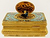 Swiss bird box with heavily patterned gilt brass case, top with bright cut engraved ornament, decorated in colorful enamels, the lid with a scene of nude bathers in a rural landscape, the bird with green, black, and blue feathers.  Late 20th century