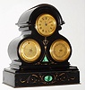 French miniature black slate mantel clock, with time, thermometer and barometer, spring driven eight day movement with jeweled lever platform escapement, matte gilt brass dials, all with gilt brass bezels and beveled glasses, Roman numeral time with painted figures and blued steel hands, thermometer and barometer also with painted figures, the polished black slate case with incised gilt ornament and faux malachite panels, base finished with a thin gilt brass molding, c1870