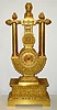 French, Empire style lyre mantel clock, with knife edge suspension of pendulum above the dial, 8 day spring driven movement numbered 210. The case profusely decorated with acanthus leaves, pineapples to the right and left of the top, and each column surmounted by a small urn with floral display, c1830
