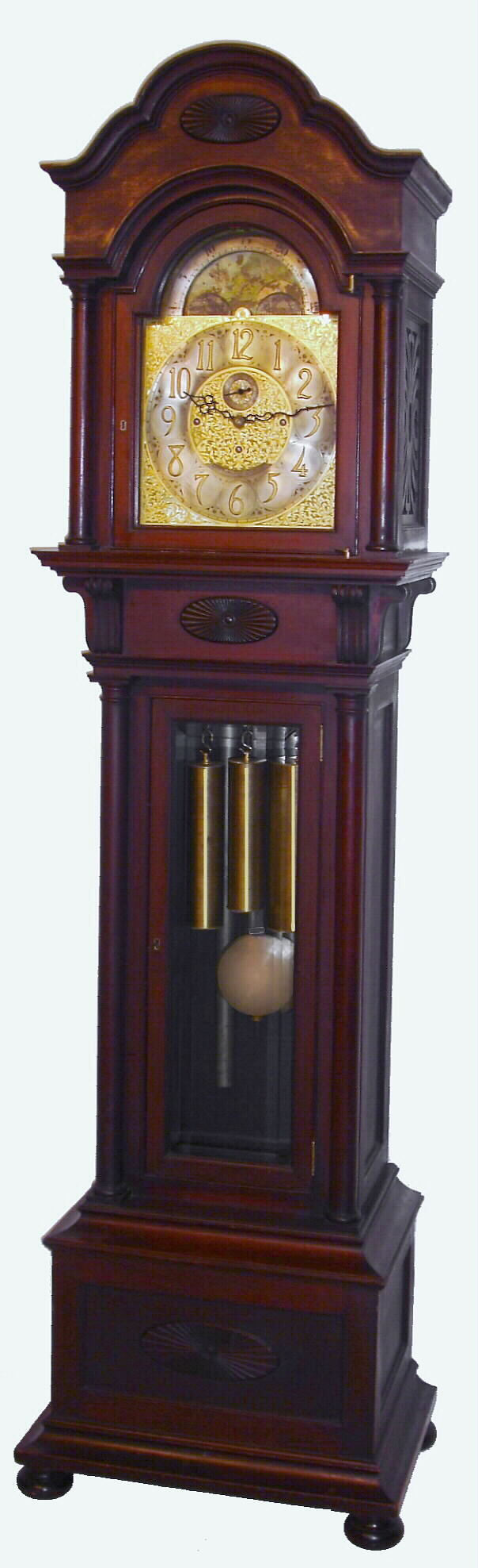Tiffany and Co., New York, 5 tube hall clock, 8 day, time, strike and chime, three weight driven English movement, Elliott design, playing single tune [Westminster] on tubes signed by Walter Durfee with patent date 1887 in mahogany case on bun feet with two full bold columns flanking trunk, beveled glass door in trunk and three ornately carved sunbursts on top of hood, above trunk and on panel in base.  The brass arched dial has a silvered chapter ring with applied brass numerals, surrounded by a finely engraved foliate mask, turned spandrels and dial center, moon phase, selection for chime or silent, and second's bit, c1905 — Antique Clocks Price Guide
