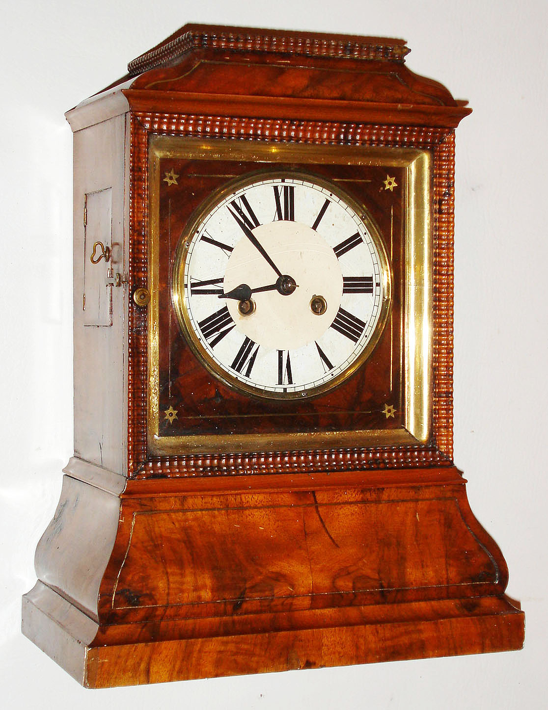 Black Forest shelf or bracket clock, spring powered time and strike movement of unknown duration, with brass bushed wooden plates, recoil escapement and count wheel striking on a gong, brass shell pendulum with wood and metal rod,  white painted Roman numeral dial with black painted steel hands, the dial mounted to a walnut veneered board with brass line and star inlay, and finished with a gilt ogee molding, protected by a ripple molded door with glass, walnut veneered spruce case with ripple molding at top, and brass inlaid bombe base, door in left side of case for strike correction, c1860 — Antique Clocks Price Guide