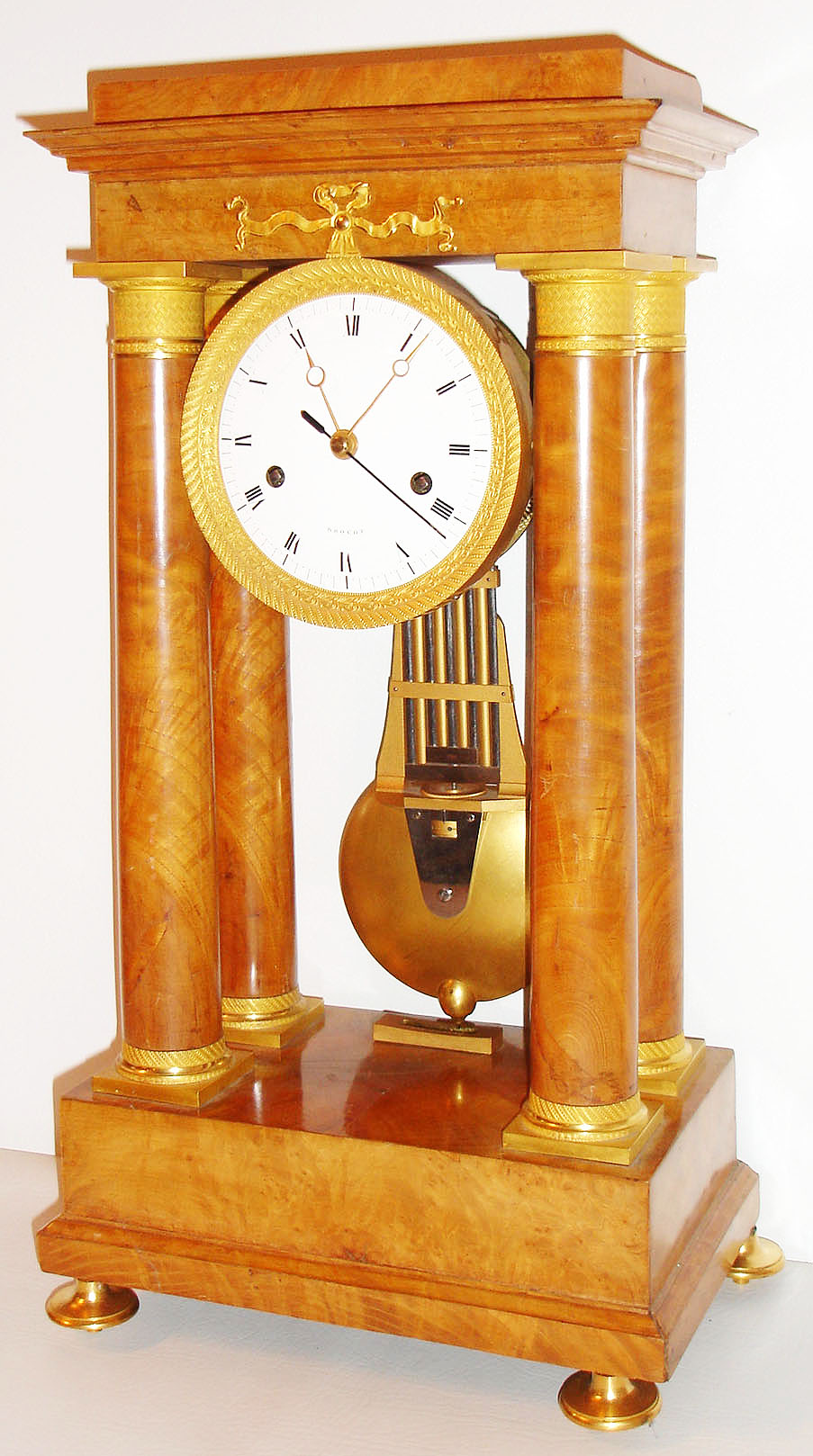 Brocot, France, large portico clock with pinwheel escapement, round time and strike movement with large barrels, possibly of two week duration, count wheel striking on a bell, crutch with fine beat adjustment, white enamel dial signed "Brocot", gilt Breguet style hands, with sweep seconds, heavy gilt brass and steel gridiron pendulum with knife edge suspension beating half seconds, the case veneered in figured ash, with gilt bezel, column mounts, and feet, with gilt beat scale, c1830 — Antique Clocks Price Guide