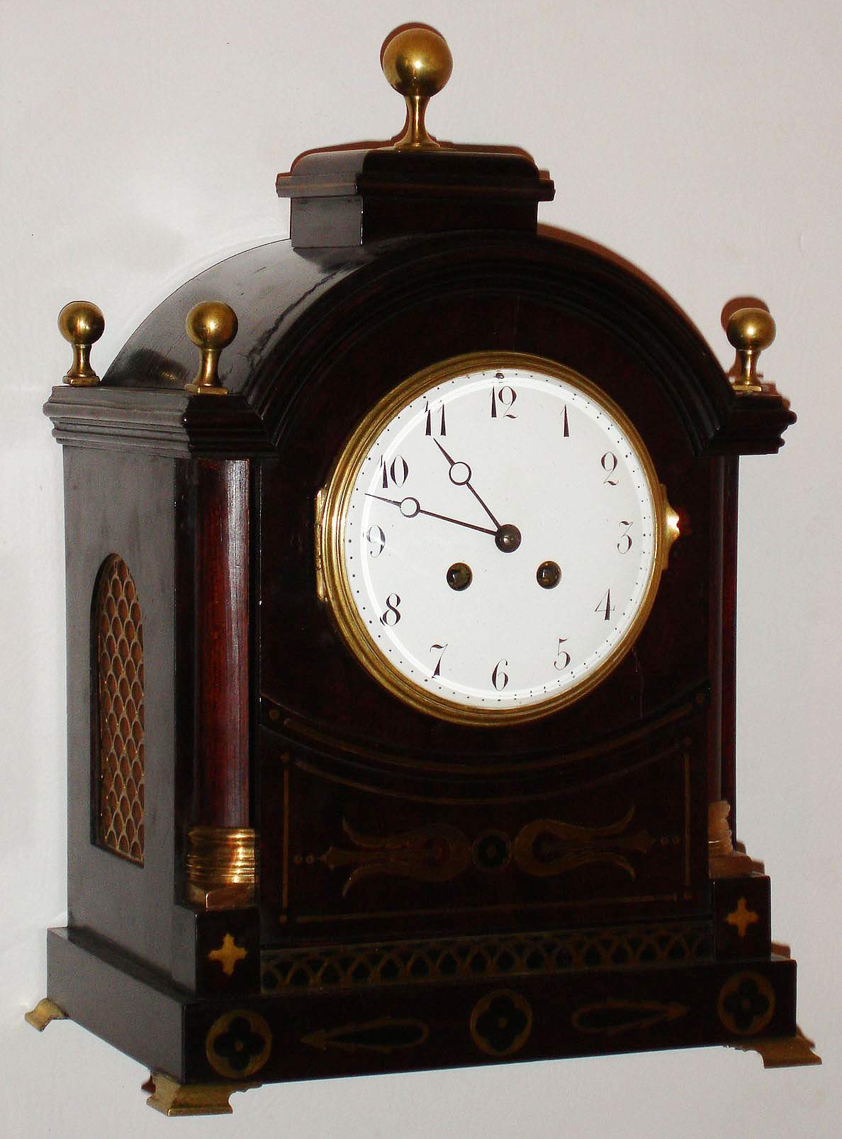 French shelf or bracket clock in the Regency style, 8 day pendule a Paris movement, recoil escapement and rack striking on a gong, white enamel Arabic numeral dial, blued steel Breguet style hands, polished brass bezel with convex beveled glass, case of mahogany and mahogany veneer with brass inlay, feet, and finials, and pierced brass fabric covered frets in each side, c1890 — Antique Clocks Price Guide