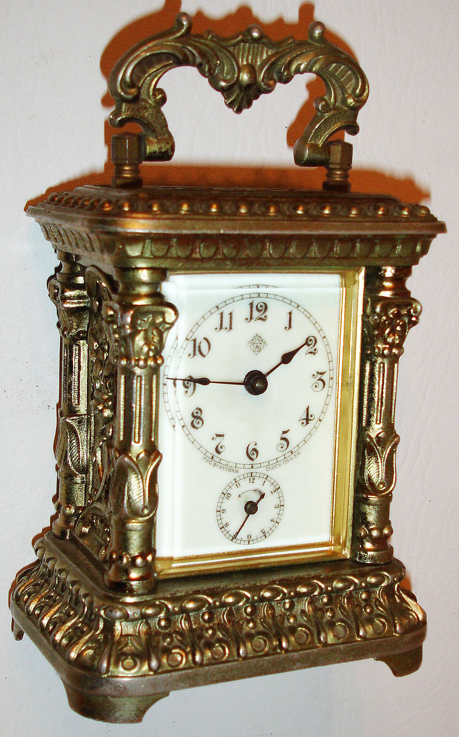 Ansonia Clock Co., Brooklyn, N.Y., "Astral" model carriage clock, ornate cast case with old lacquer finish, 30 hour time and alarm movement, white enamel Arabic numeral dial with blued steel hands, under a thick beveled glass, with key c1905 — Antique Clocks Price Guide
