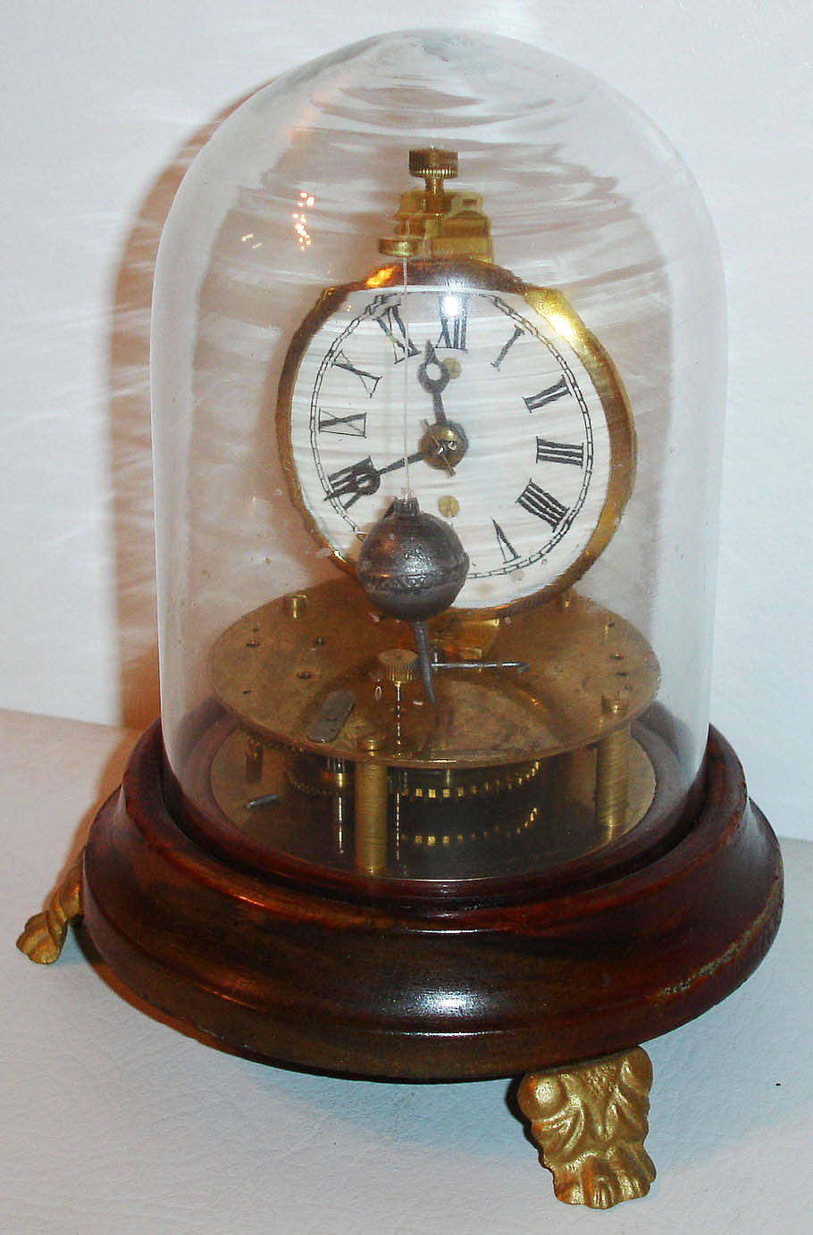 Reproduction of Briggs pat. rotary pendulum timepiece (30-hour), on a walnut base with 3 cast feet and iron winder under base, with glass dome. C.2010 — Antique Clocks Price Guide
