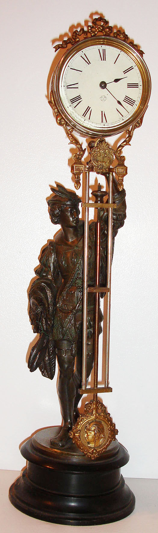 Ansonia Clock Co., Brooklyn, N.Y., "Fisherman" swinger mystery clock, eight day time only movement contained in a nickel plated cylindrical case with thick beveled glass, paper Roman numeral dial, blued steel hands, clock case with ornamental band which attaches it to the pendulum, cast pendulum with Centurion in profile, the spelter fisherman in a silver gray finish, on a molded, black enameled cast iron base, c1885 — Antique Clocks Price Guide