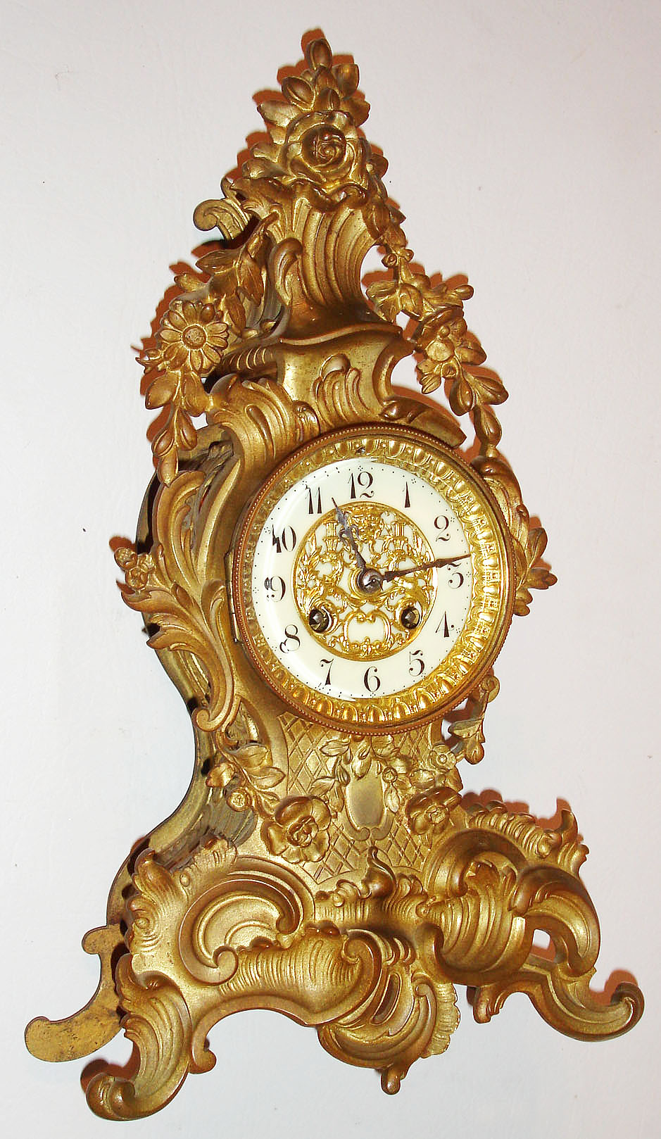 France, gilt cast brass mantel clock in the rococo style, the case decorated with acanthus, C scrolls and flower garlands, white enamel Arabic numeral dial with gilt ornamental cast center, blued steel hands, gilt bezel with thick beveled glass, 8 day, time and strike, pendule a Paris movement signed "Japy Freres", c1910 — Antique Clocks Price Guide