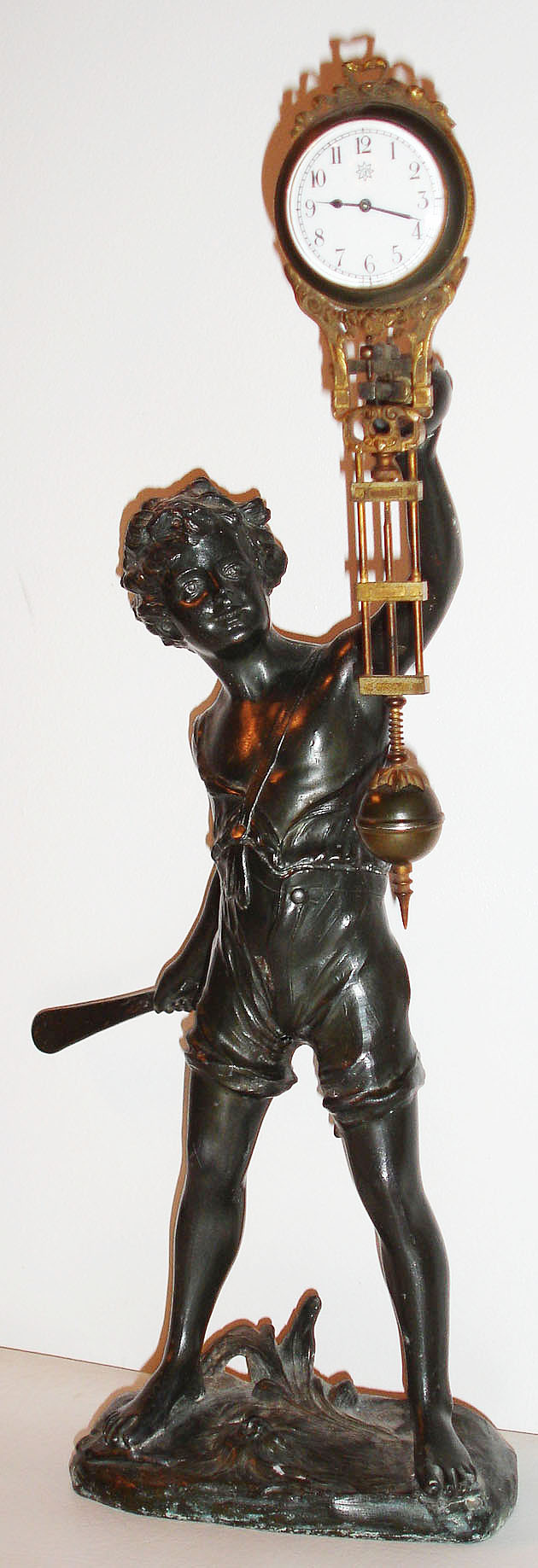 Junghans, Germany, "Bat Boy" novelty swinger, patinated spelter figure of a boy with bat and ball supporting the gilt and patinated swinging eight day clock/ pendulum, white enamel Arabic numeral dial with Junghans logo, blued steel hands c1920 — Antique Clocks Price Guide