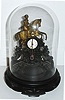 Austria, thirty hour Zappler clock for the English market, white enamel Roman numeral dial, gilt hands, decorative pendulum, cast iron case with Queen Victoria on horseback, the lower section with rococo ornament, a crown, and embossed at the bottom Victoria 1, mounted to a wooden base, under a glass dome c1850