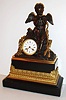 French mantel clock, gilt and patinated bronze and polished black slate, with dark patinated figure of a sitting Cupid, holding a gilt bird in his cupped hands, his bow and quiver to his left and gilt foliage to his right, the polished black slate base with a gilt bronze section cast with egg and dart, acanthus and modified anthemion ornament, 8 day, time and strike, pendule a Paris movement, silk thread suspension, recoil escapement and count wheel striking, Roman numeral white enamel dial signed "Pommier a Luneville", bezel is removed by rotating until two pins line up with notches that release them, and blued steel Breguet style hands, c1830