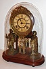 Ansonia Clock Co., New York, NY, "Crystal Palace No. 1 Extra", walnut base and back mounted with silvered figures of a fisherman and a hunter, flanking a central mirror, paper Roman numeral dial with blued steel hands, surrounded by a fancy lacquered cast brass bezel, eight day time and strike movement with Davies patent style pendulum, under a glass dome, c. 1880
