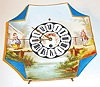 France or Germany, earthenware plate clock with easel back, square, gilt edge with folded corners, with a rural scene in polychrome over glaze enamels, featuring a man and a woman on opposite sides of a bridge, each dressed in 18th century style clothing, Roman numeral dial with brass hands, the dial center decorated with a small trophy featuring musical instruments 8 day, time only, pendulum movement with tic tac escapement, c1900