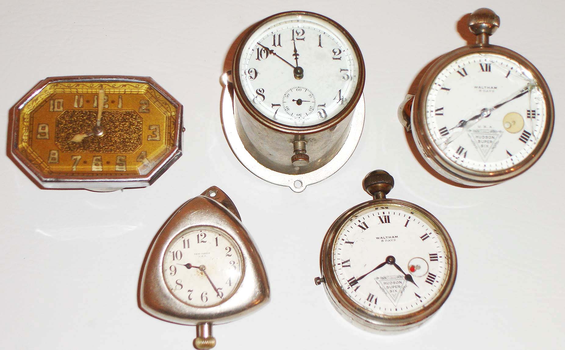 Clocks- 5 (Five) Automobile: two 8 days, Waltham with Hudson Super Six enamel dials, one New Haven in a triangular dash mount case, one deco style in an elongated octagonal case, and one unmarked in a cylindrical dash mount case with white enamel dial, early 20th century — Antique Clocks Price Guide