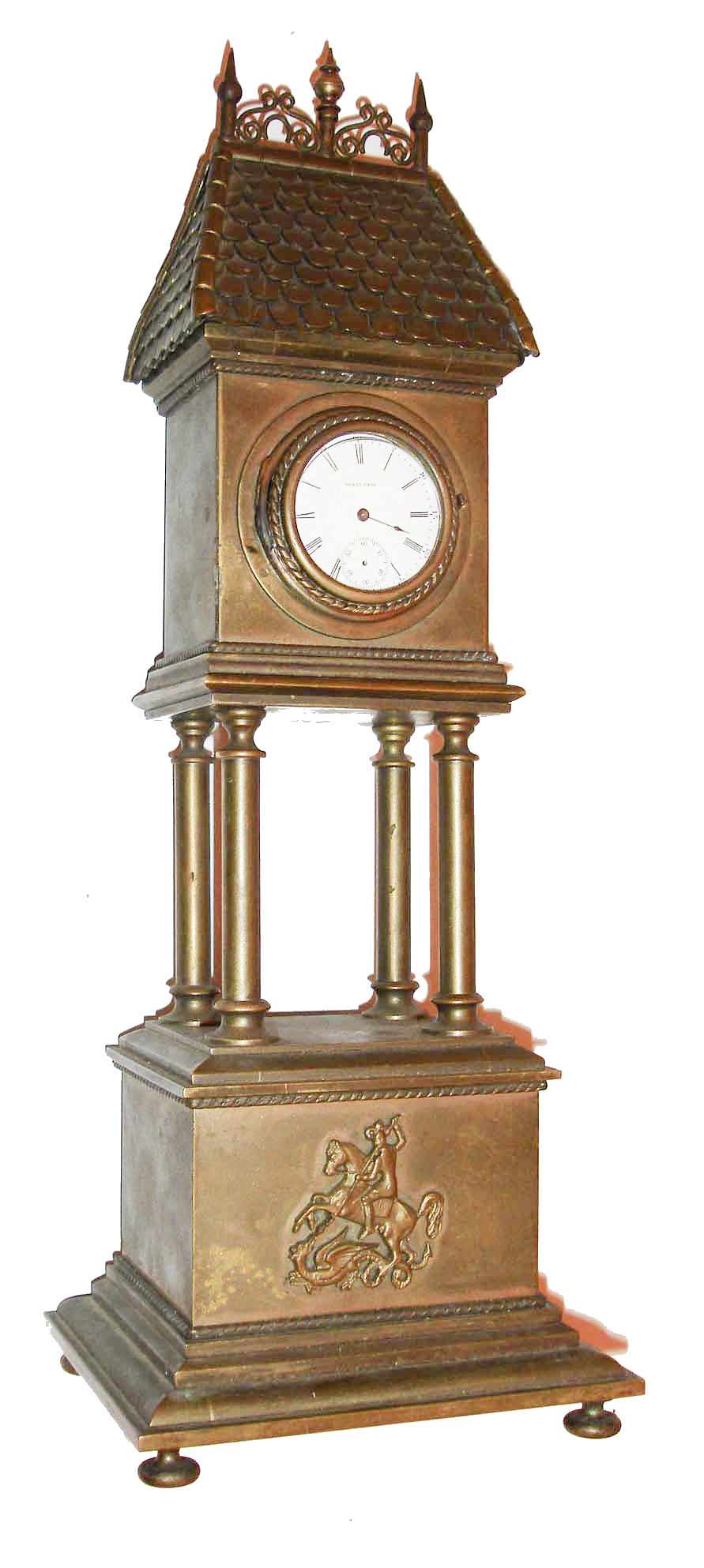 Desk clock, heavy brass case in the form of a clock tower, square molded base with relief of St. George slaying a dragon, the base with 4 columns supporting the upper portion, with rope molded bezel and convex glass, containing a 17 jewel Waltham model 1899 watch movement, the roof covered in brass "tiles", and the top with short, lightning rod style ornaments, c1900 — Antique Clocks Price Guide