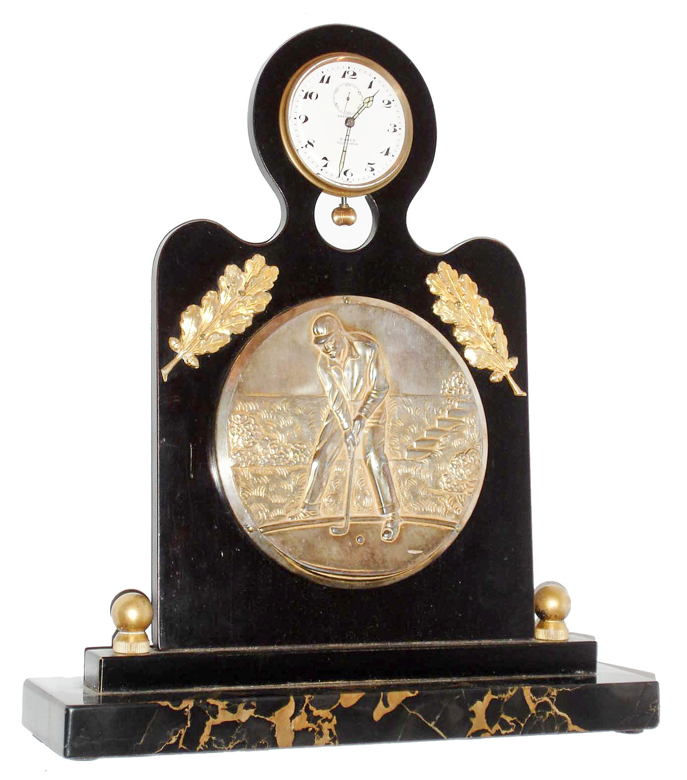 Angelus Watch Co., Switzerland, for Tiffany &amp; Co., New York, golf themed desk clock with 8 days, minute repeating clock, the veined black marble base supporting an ebonized wood stand, mounted with a gilt repousse style plaque depicting a golfer putting, with two applied gilt branches with oak leaves above the plaque, and with clock mounted at the top, the 8 day, 15 jewel, minute repeating nickel plate movement with centrifugal governor, lever escapement with cut bimetallic balance, white enamel dial with Arabic numerals, signed "Tiffany &amp; Co. 8 Days Repeater", with blued steel luminous hands, back of case dated May 14, 1932 — Antique Clocks Price Guide
